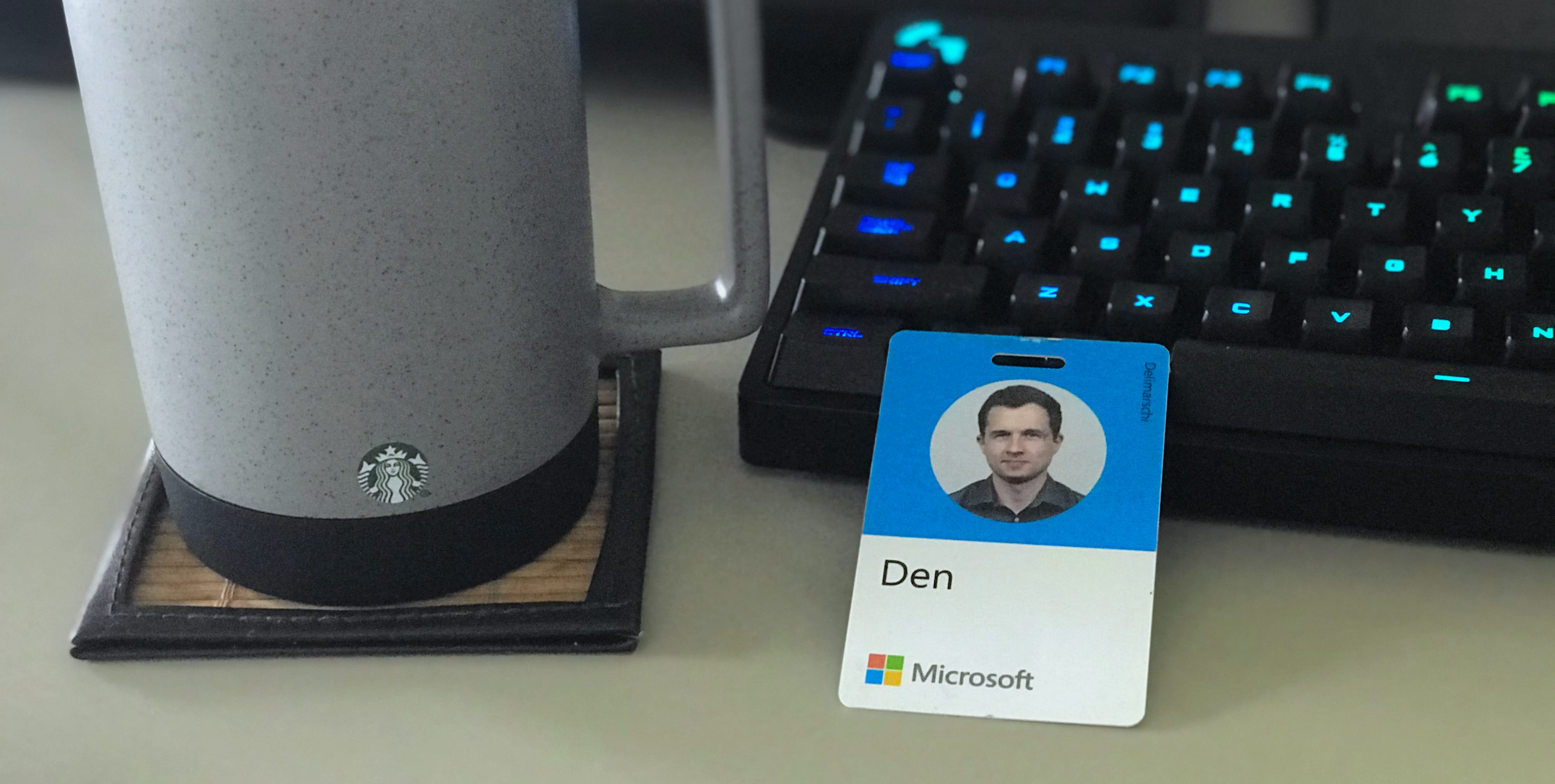 Microsoft badge next to a coffee cup and a keyboard
