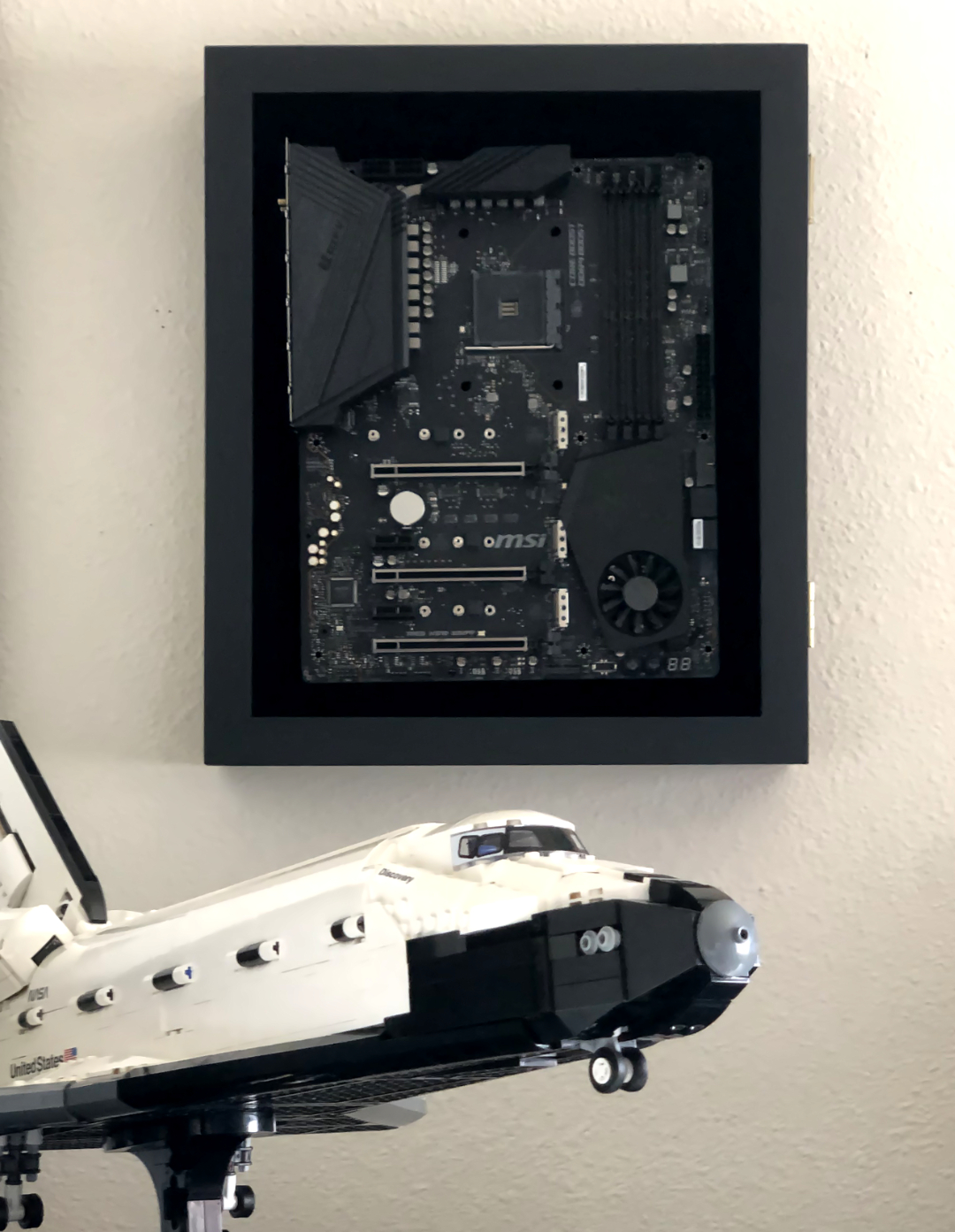 Wall-mounted motherboard with a LEGO space shuttle in front of it